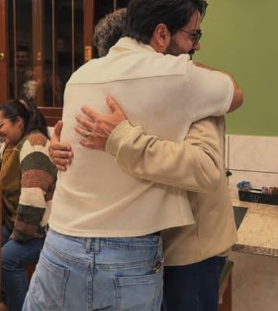 Dois amigos se abraçando no salão do Sabor & Prosa, de paredes verdes